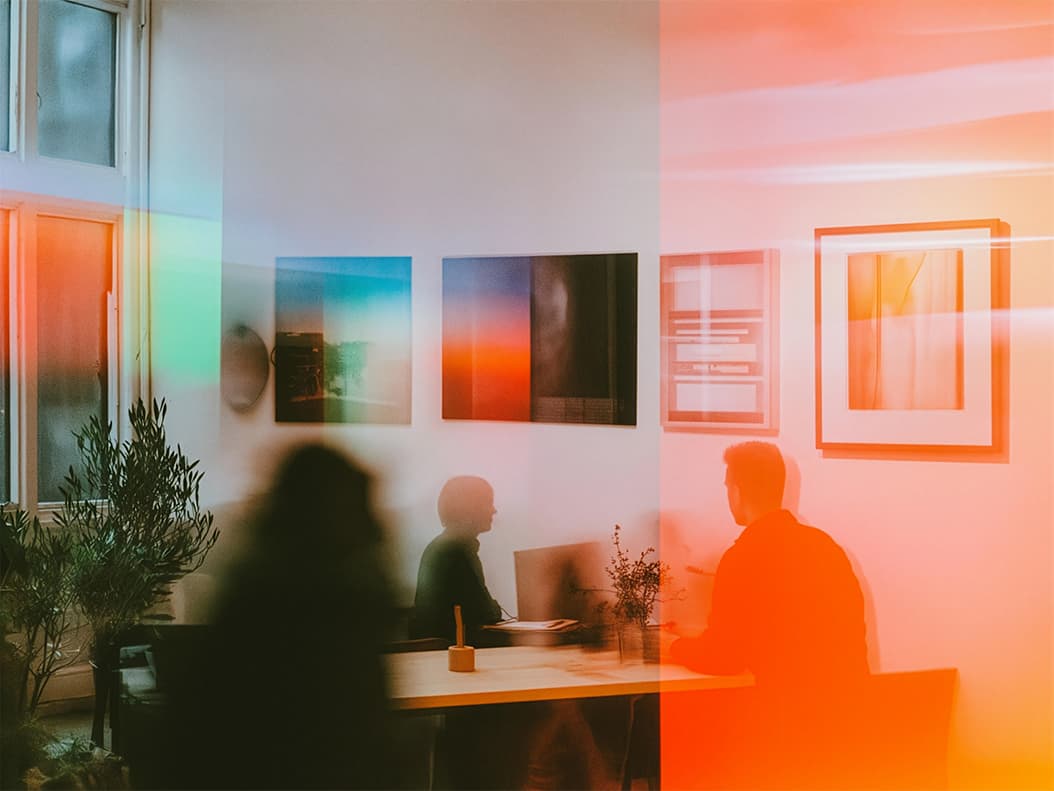 Customer Engagement & Experience service image showing a Modern office with warm lighting, abstract art, and blurred figures in conversation.